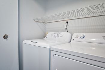 a washer and dryer in a laundry room with a shelf over the top